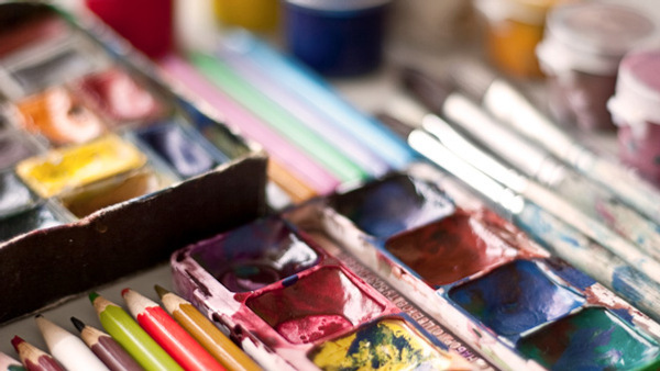 En närbild av en låda med färg och penslar.