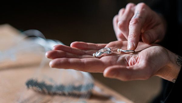 Ringar i organiska former i silver i en utsträckt hand.