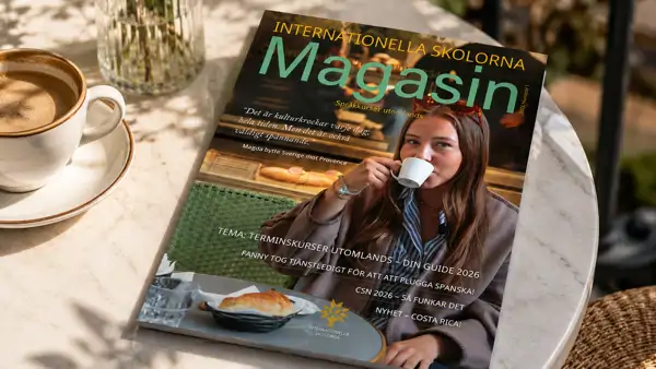 Internationella Skolornas magasin som ligger på ett bord bredvid en kopp kaffe.