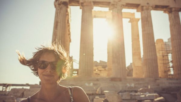 Person i solglasögon framför Parthenon i Aten, med solen i bakgrunden, efter kurs i grekiska på Folkuniversitetet