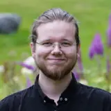 En man står framför lila blommor.