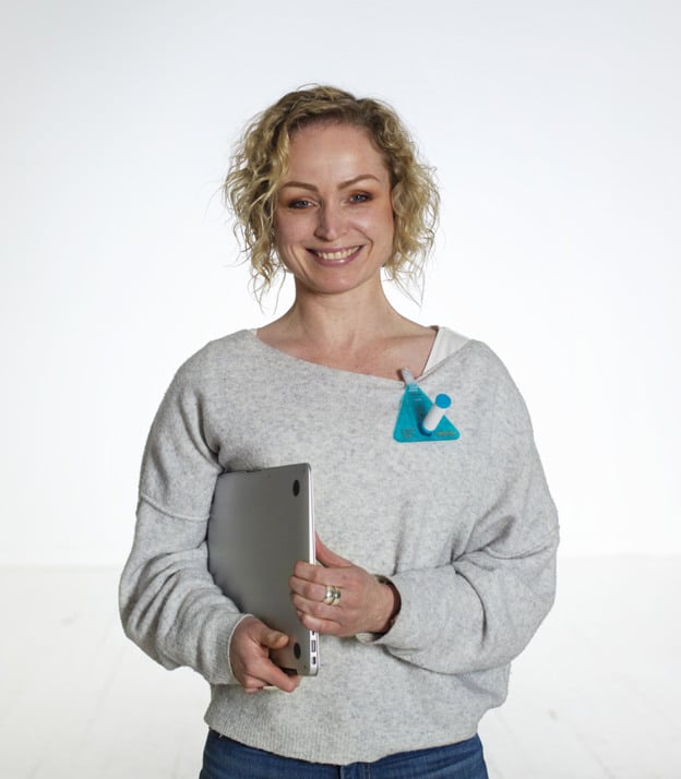 En kvinna som håller i en ipad och ler mot kameran.