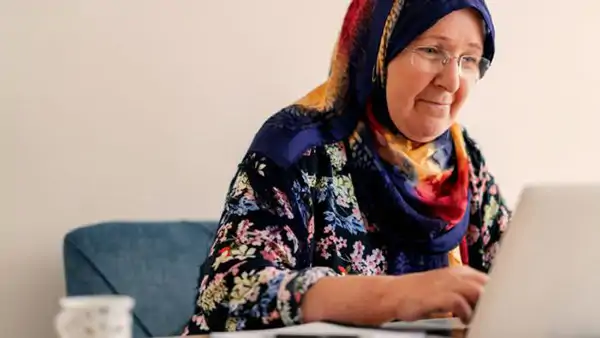 Older woman sitting at a computer, focused and engaged during a lesson.