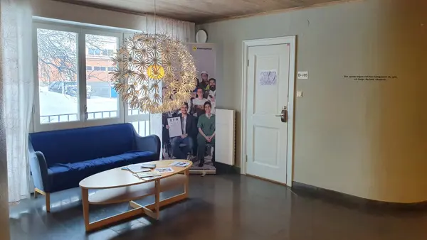 Ett vardagsrum fyllt med m&ouml;bler och en ljuskrona.