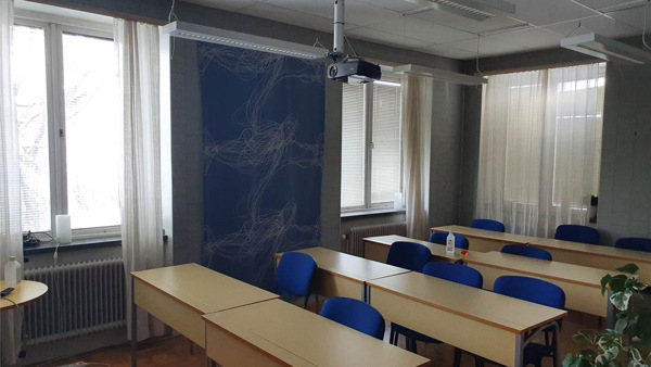 Ett klassrum med bänkar och stolar framför ett fönster.