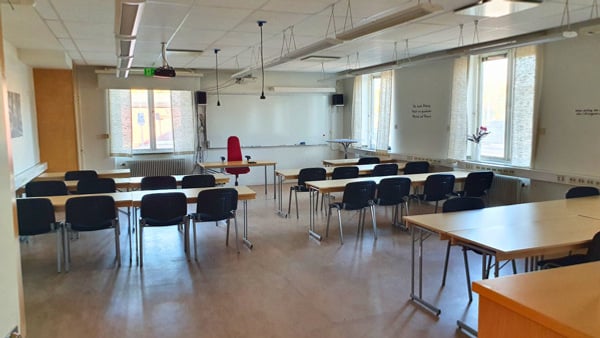 Ett tomt klassrum med bänkar och stolar.