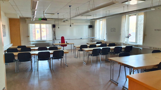 Ett tomt klassrum med bänkar och stolar.