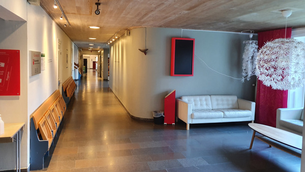 En lång korridor med en vit soffa och en rödvit stol.