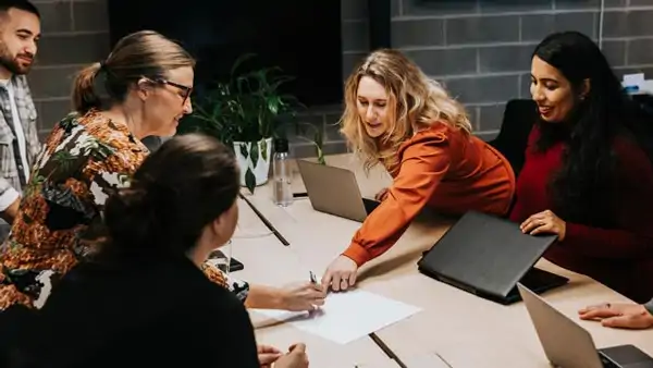Personer vid ett skrivbord som diskuterar 
