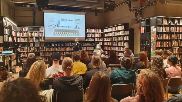 En grupp människor i ett bibliotek som tittar på en presentation.
