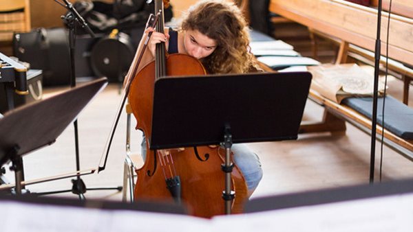 En kvinnlig cellist studerar ett notblad på Gotlands Tonsättarskola