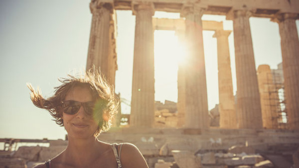 Person i solglasögon framför Parthenon i Aten, med solen i bakgrunden, efter kurs i grekiska på Folkuniversitetet