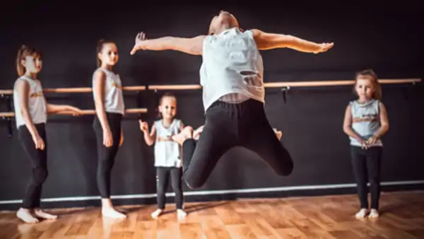Teacher and group of children exercising dancing and ballet in dance school