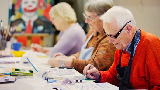 äldre man och två kvinnor målar vid ett bord