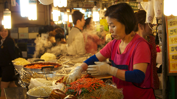 Koreansk kvinna lagar mat på marknad i Seoul i Sydkorea