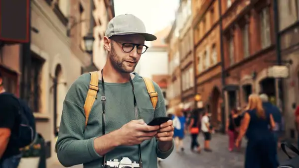 Man med mobiltelefon i handen stående på stadsgata. 