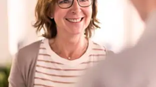 En kvinna ler medan hon pratar med en man.