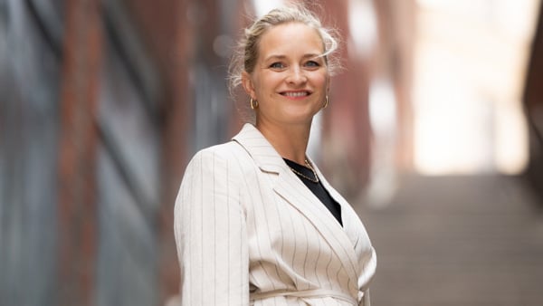 En kvinna i vit kostym står på några trappsteg.