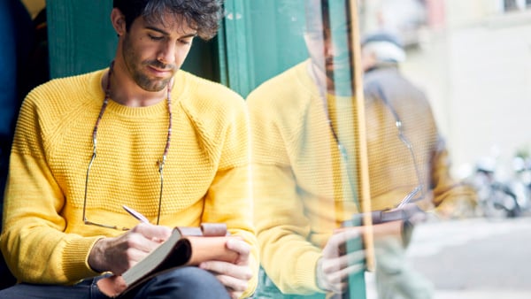 Kvinna sitter i soffan hemma med laptop i knäet och tittar på skärmen.