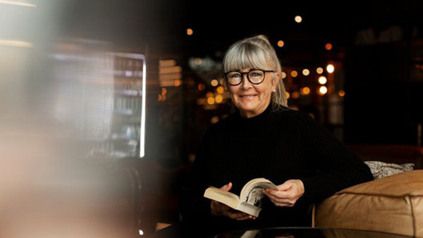 Kvinna bläddrar i en bok i mörk inomhusmiljö - på kurs i romani