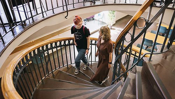 En elev och en lärare på Kungstensgymnasiet går uppför en trapp i skolan.