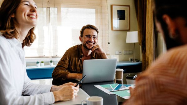 Tre personer sitter vid ett bord med sina datorer