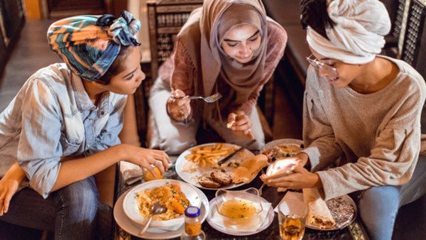 Muslim young women having a lunch break together in an Arab restaurant
