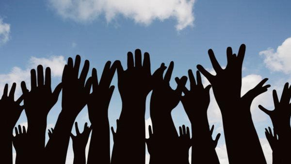 Siluetter av uppsträckta händer mot blå himmel - symbol för föreningslivs, engagemang och demokrati