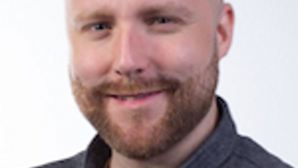 En flintskallig man med bocksk&auml;gg ler mot kameran.