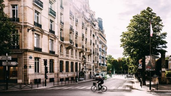 En man cyklar på en gata i Paris dit du kan åka på språkresa för vuxna och läsa franska