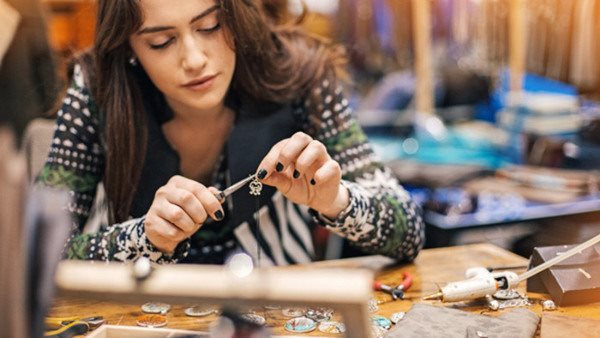 Young woman creating handmade jewelry in her studio