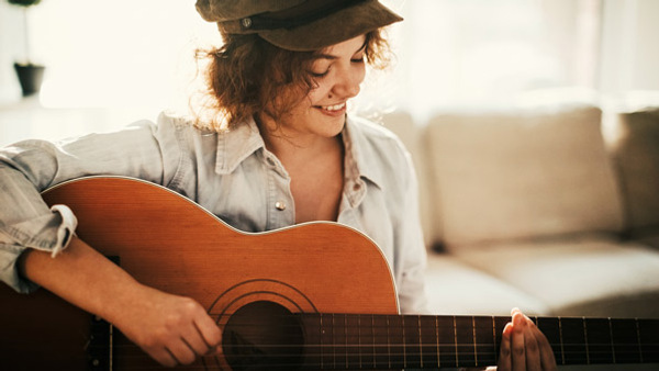 En person med hatt som spelar gitarr.