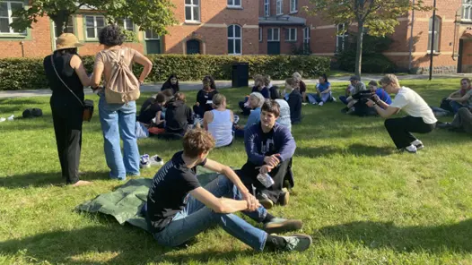 En grupp människor som sitter på ett grönskande fält.