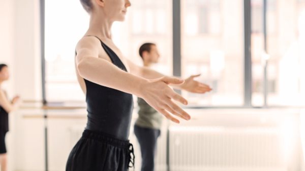 Midsection of ballet dancer rehearsing at studio. Side view of young female are practicing on dance floor. She is wearing sportswear.