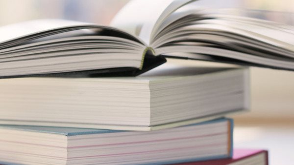 Uppslagen bok ovanpå bokstapel - från kurs i filosofi