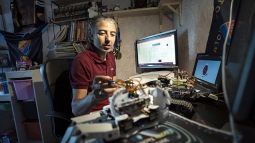 En man sitter vid en dator och arbetar med kablar och teknik