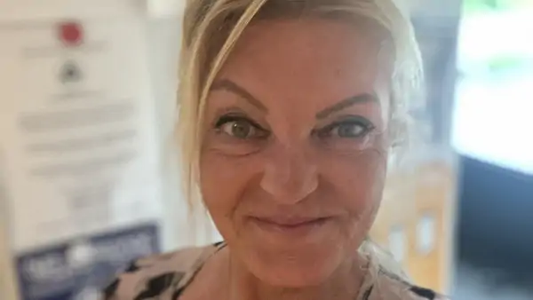 Kvinna med blont hår som tittar in i kameran