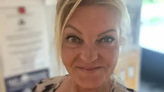 Kvinna med blont hår som tittar in i kameran