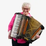 En kvinna håller i ett dragspel mot en vit bakgrund.