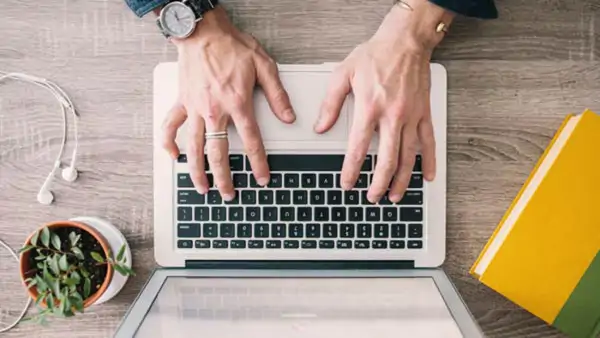Overhead view of hands typing on a small laptop