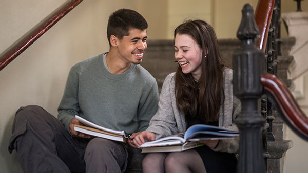 Studenter sitter utomhus och studerar tillsammans. 