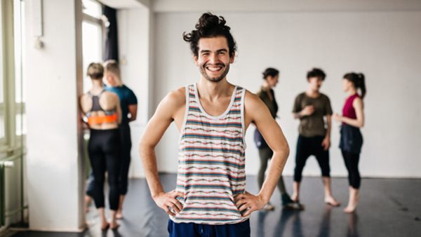 Portrait of a young male dancer standing in a dance studio and smiling at camera
