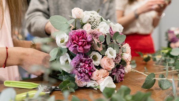 Deltagare binder en bukett med färgglada snittblommor och eukalyptus under en floristkurs