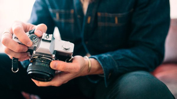 Person justerar inställningarna på en systemkamera under en fotokurs
