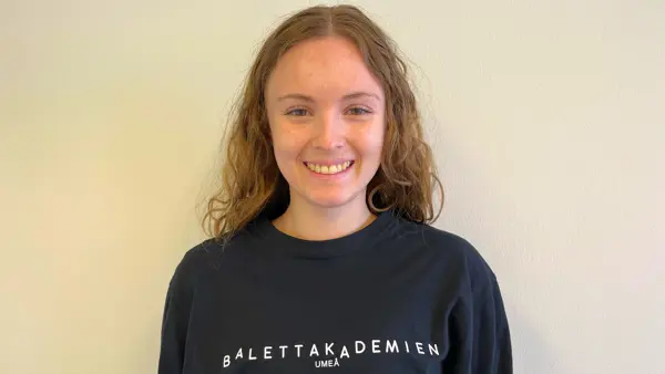 En ung flicka som bär en svart sweatshirt med ordet balettakademien på.