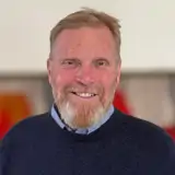 En man i blå tröja står i ett rum.