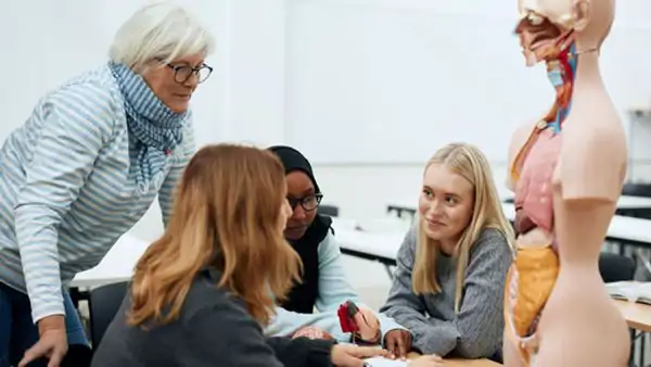 Lärare och elever samtalar kring en anatomisk modell i ett klassrum på Cultus
