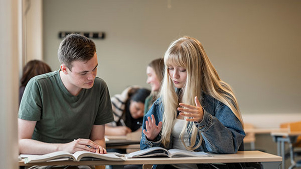 Två elever i klassrummet, diskuterar. 