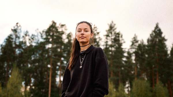 En kvinna som står vid en skog.