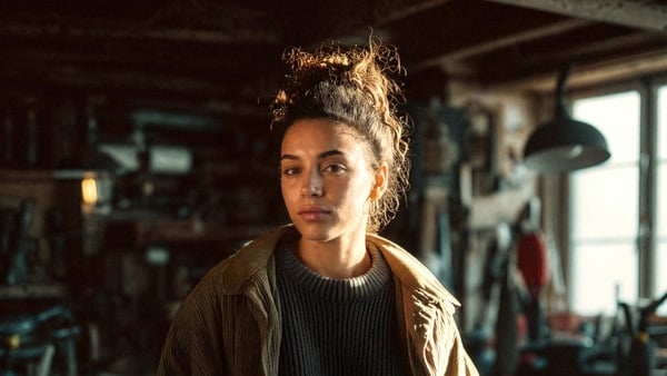 En kvinna som står i ett rum fullt av verktyg.